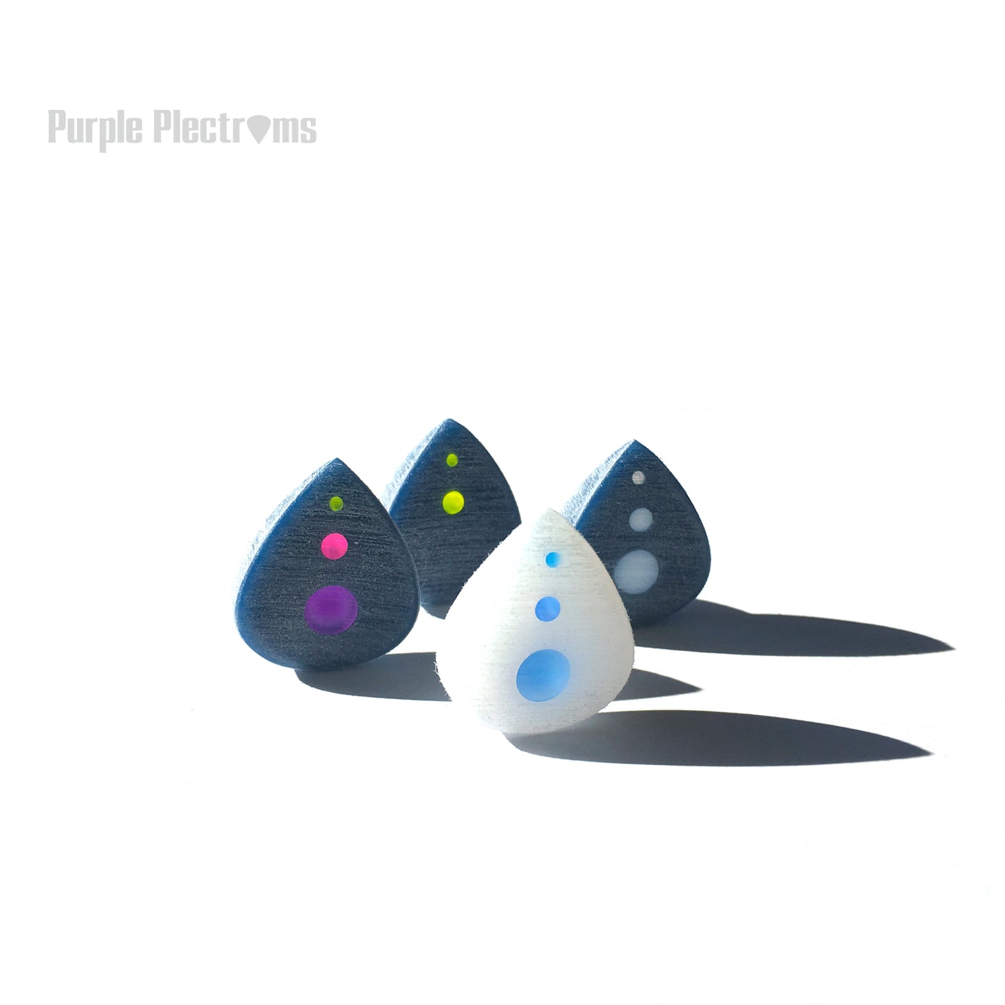 group of four small guitar picks with multicolor optics