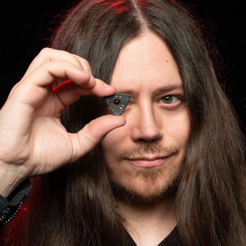 Doug Weiand looking through the holes of his guitar pick