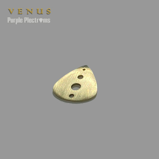 brass guitar pick with holes drilled across the spine bathed in sunlight