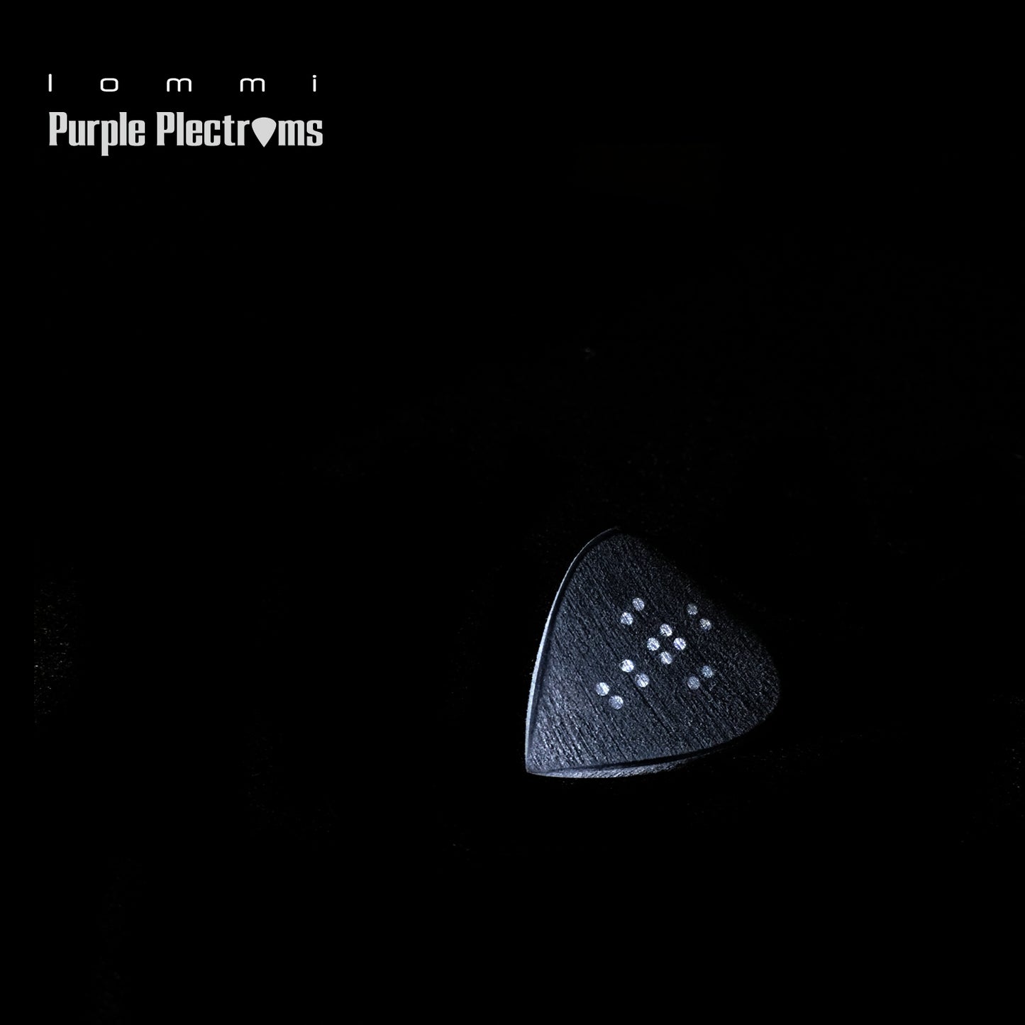 black guitar pick with metal inserts in shape of a cross against a dark background