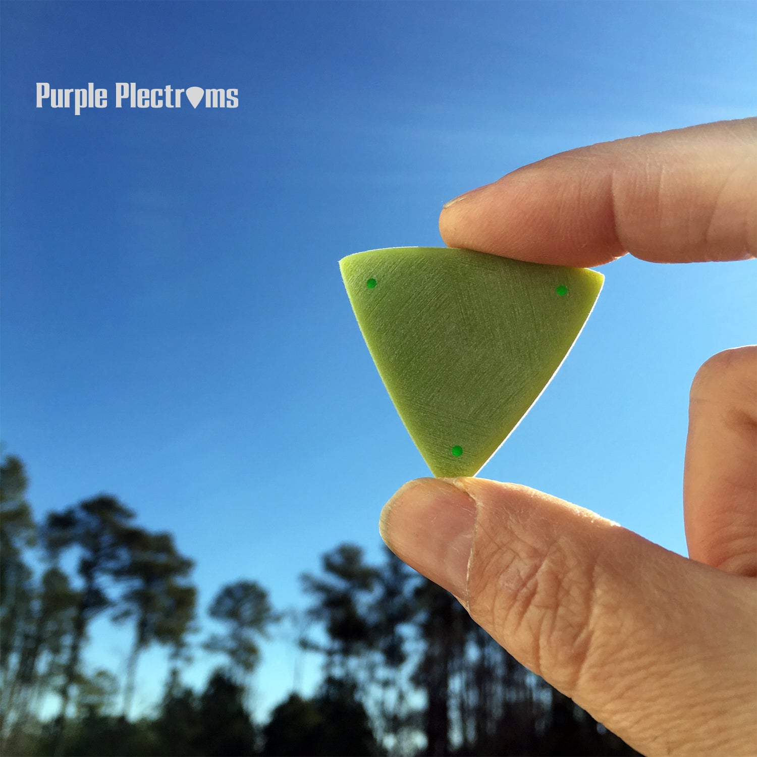 green triangular guitar pick against a blue sky background