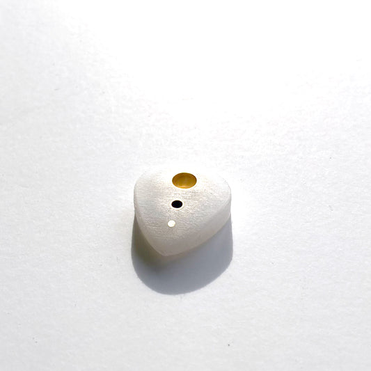 white guitar pick with brass inserts along the spine