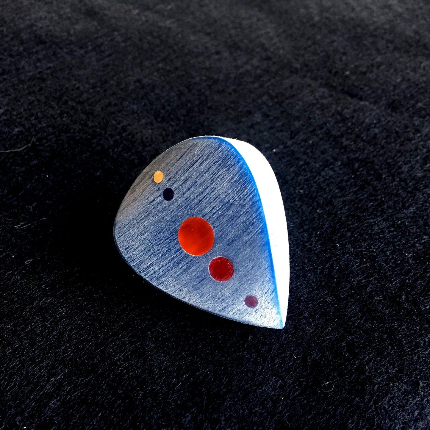 blue big and thick guitar pick with red color optics along the spine