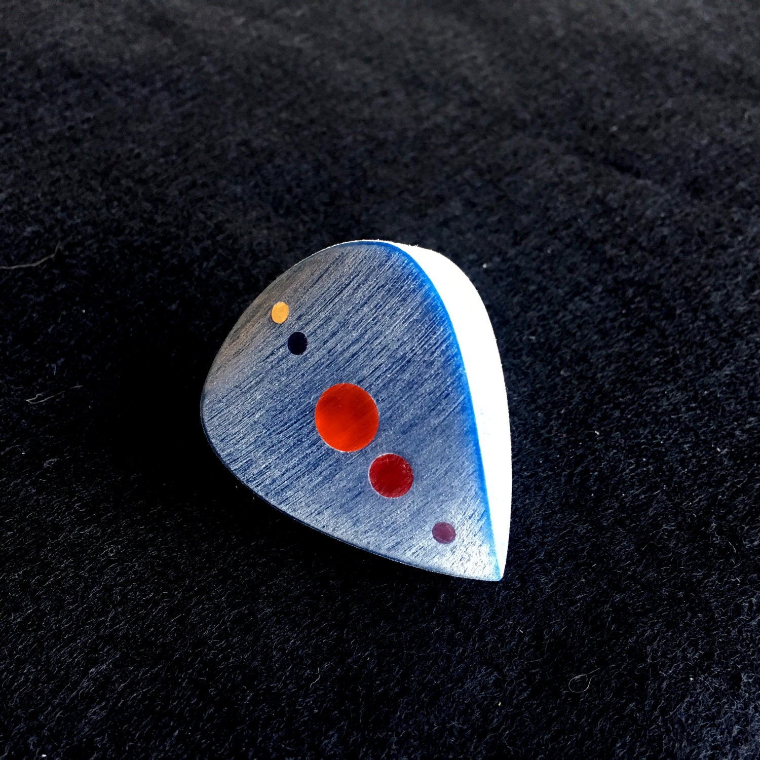blue big and thick guitar pick with red color optics along the spine