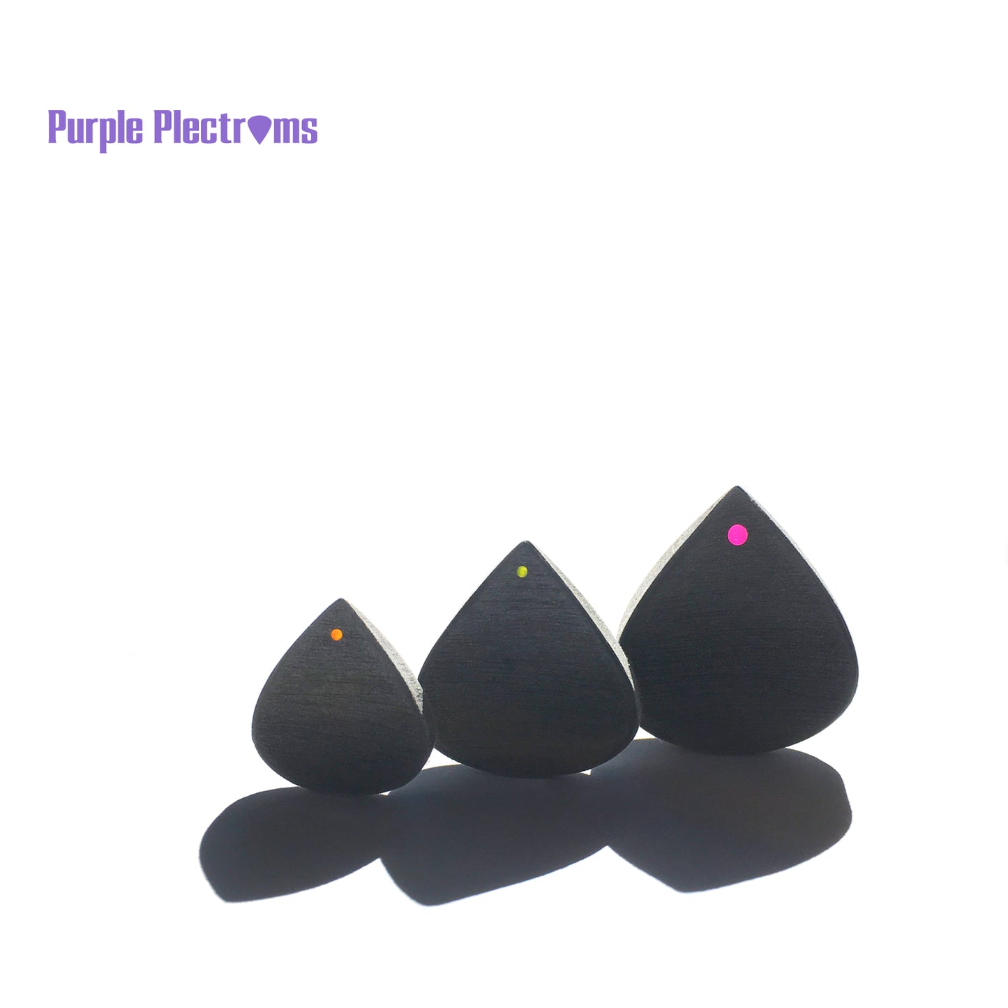 trio of small to bigger guitar picks in sunlight