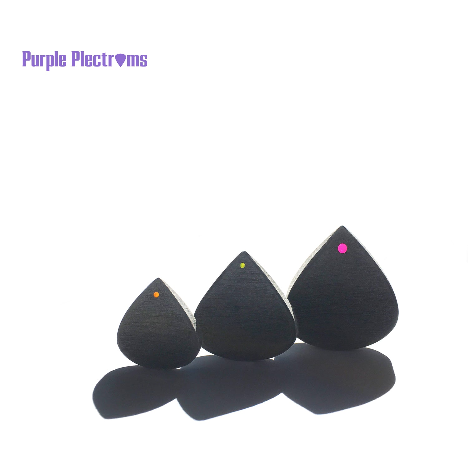 trio of small to bigger guitar picks in sunlight